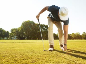 Golfare som plockar upp boll