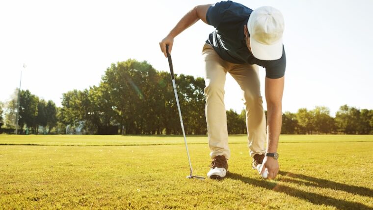 Golfare som plockar upp boll