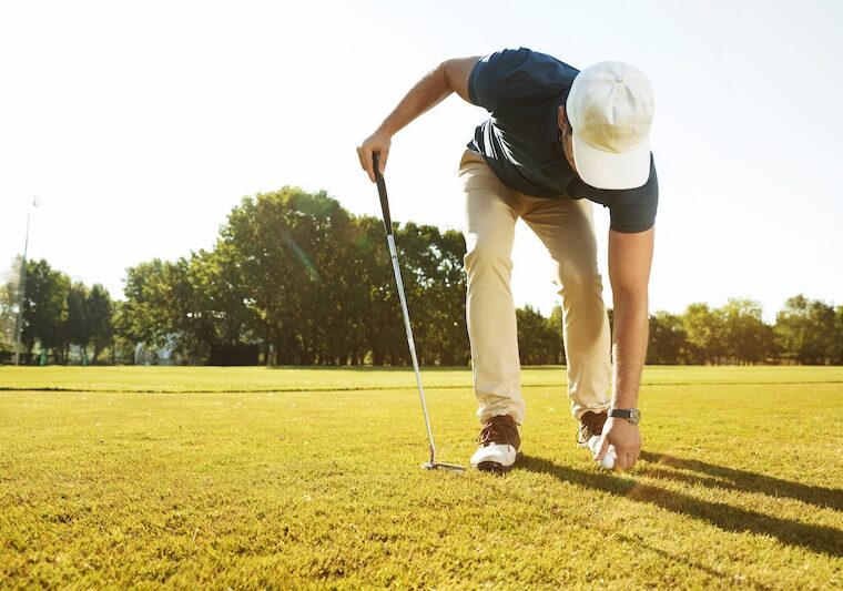 Golfare som plockar upp boll